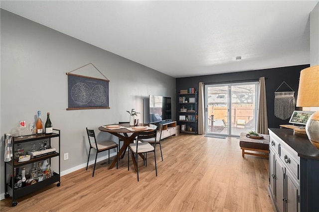 dining space with light wood-type flooring and baseboards