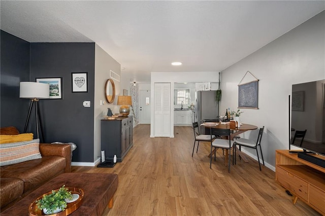 living area featuring light wood finished floors, visible vents, and baseboards