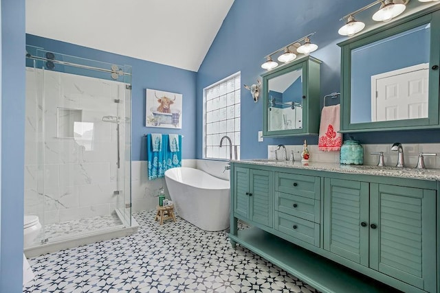 full bathroom with double vanity, lofted ceiling, a stall shower, a sink, and a freestanding tub