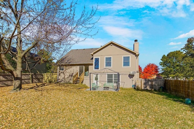 back of house featuring entry steps, a fenced backyard, a chimney, and a yard