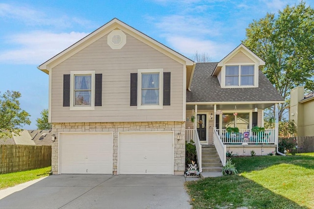 view of front of property featuring a porch, fence, driveway, stone siding, and a front yard