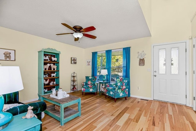 interior space featuring ceiling fan, a textured ceiling, light wood-type flooring, and baseboards