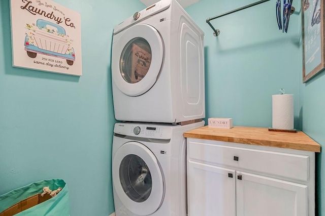 laundry room featuring cabinet space and stacked washer / drying machine