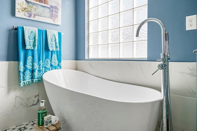 full bathroom featuring a soaking tub and tile walls