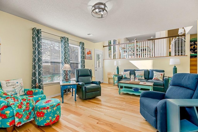 living room featuring visible vents, a textured ceiling, baseboards, and wood finished floors