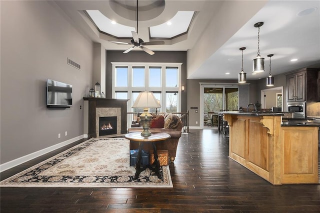 living area with visible vents, a tile fireplace, dark wood-type flooring, and baseboards