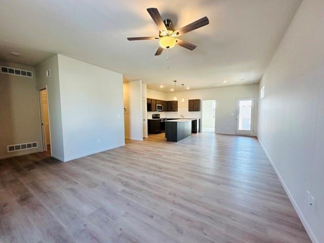 unfurnished living room featuring wood finished floors, visible vents, and baseboards