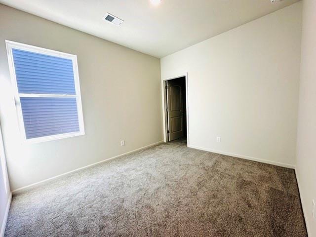 unfurnished room featuring carpet, visible vents, and baseboards