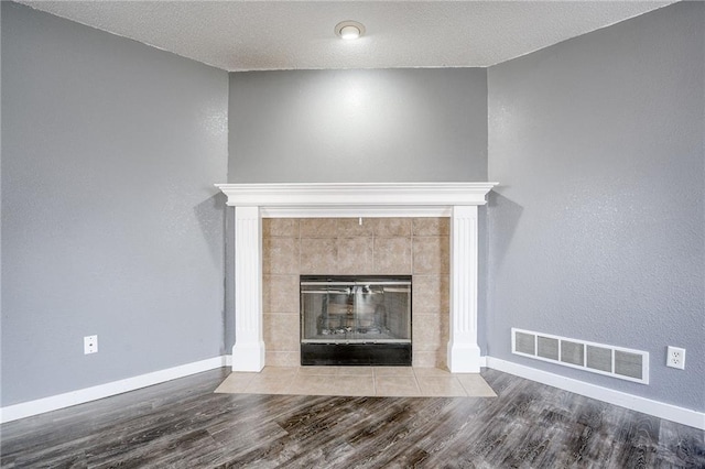 details featuring baseboards, visible vents, wood finished floors, and a tile fireplace