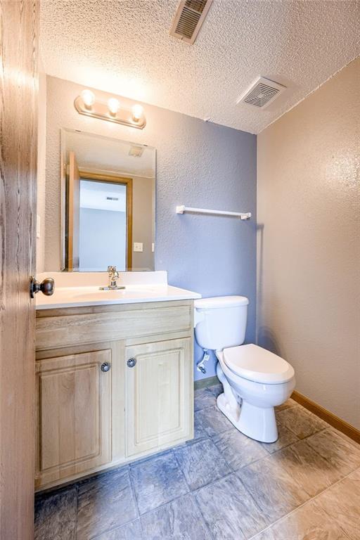 half bathroom with toilet, baseboards, and visible vents