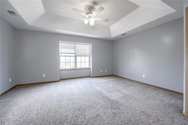 spare room featuring a raised ceiling, ceiling fan, a textured ceiling, and baseboards