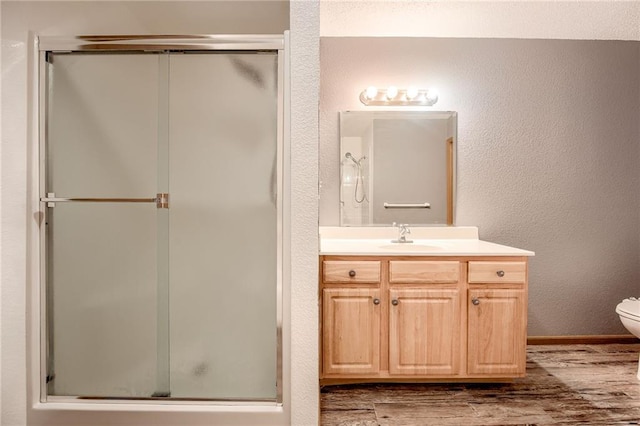 full bath with vanity, wood finished floors, a shower stall, and toilet