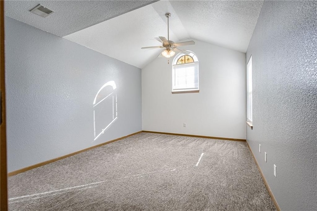 additional living space featuring a textured wall, lofted ceiling, ceiling fan, a textured ceiling, and carpet floors