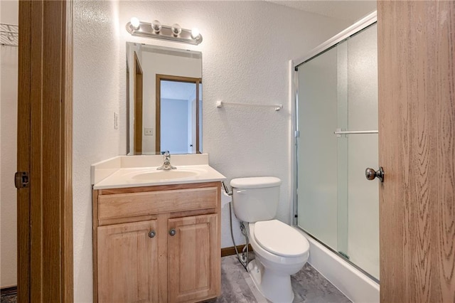 bathroom featuring toilet, a textured wall, a shower stall, and vanity