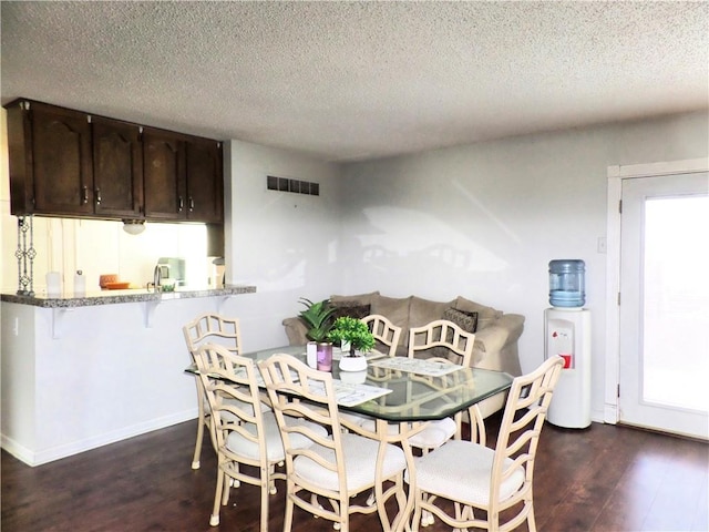 dining space with visible vents, a textured ceiling, a healthy amount of sunlight, and dark wood-style flooring