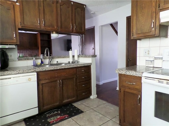 kitchen with tasteful backsplash, under cabinet range hood, light tile patterned floors, white appliances, and a sink