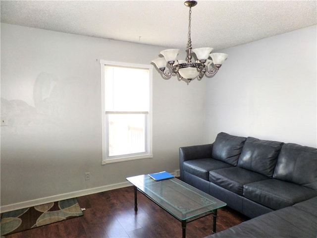 living area featuring dark wood-style floors, a notable chandelier, a textured ceiling, and baseboards