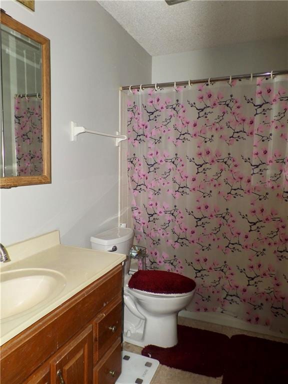 bathroom featuring vanity, curtained shower, toilet, and a textured ceiling