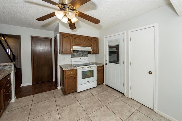 kitchen featuring light tile patterned floors, electric range, under cabinet range hood, a textured ceiling, and tasteful backsplash