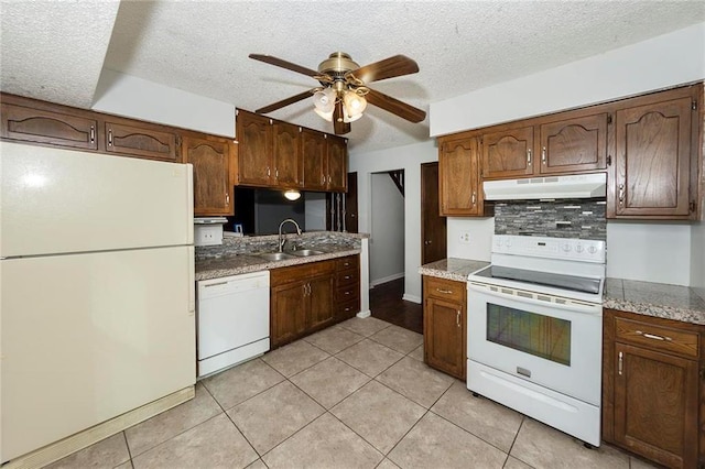 kitchen featuring white appliances, light tile patterned floors, a sink, under cabinet range hood, and tasteful backsplash