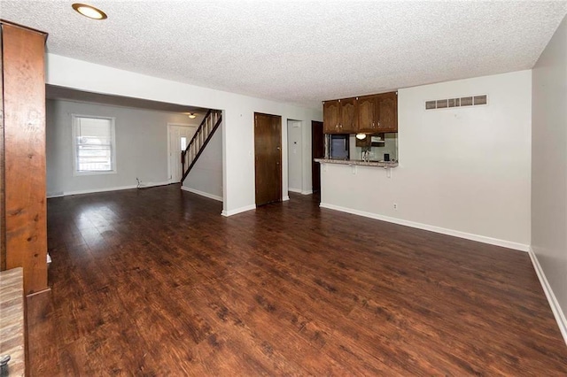 unfurnished living room with stairs, dark wood-style floors, visible vents, and baseboards