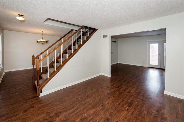 interior space with a chandelier, baseboards, a textured ceiling, and wood finished floors