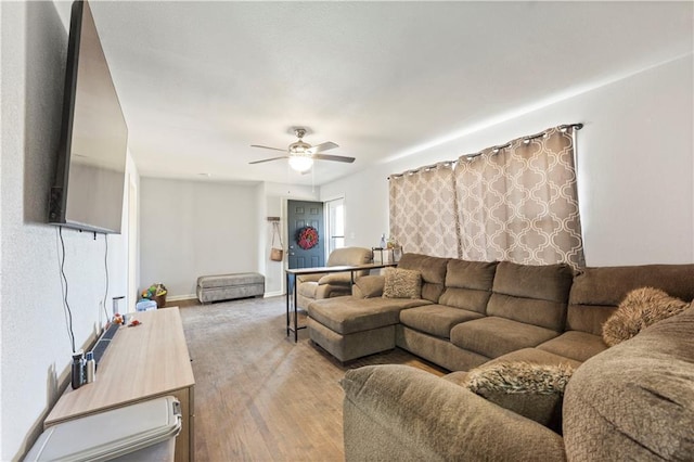 living area featuring ceiling fan, baseboards, and wood finished floors