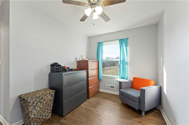 living area featuring a ceiling fan, wood finished floors, visible vents, and baseboards