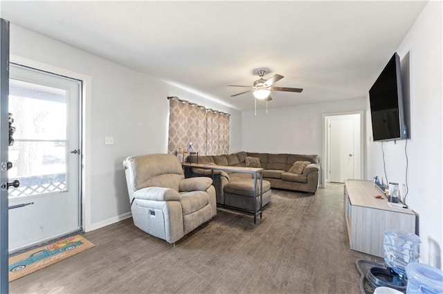 living room with ceiling fan, baseboards, and wood finished floors