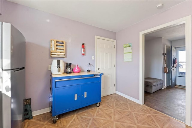 kitchen featuring blue cabinets, baseboards, light countertops, and freestanding refrigerator