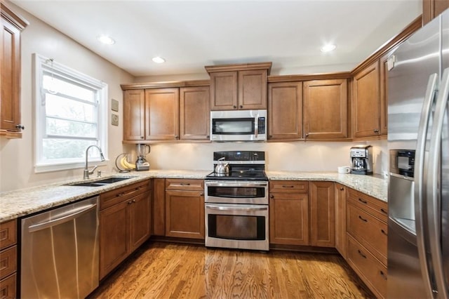 7345 Booth St, Prairie Village, KS 66208 - kitchen with a sink, light wood-type flooring, brown cabinets, light stone countertops, and appliances with stainless steel finishes