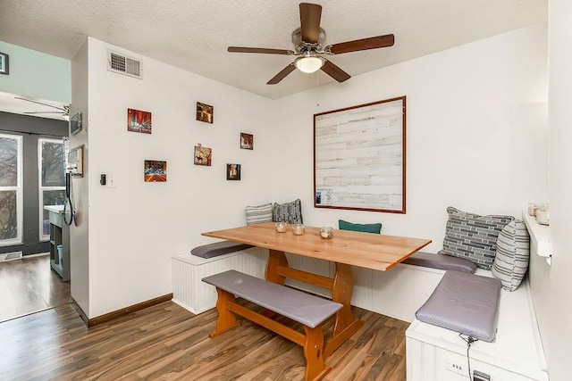 dining area with breakfast area, visible vents, a textured ceiling, wood finished floors, and baseboards