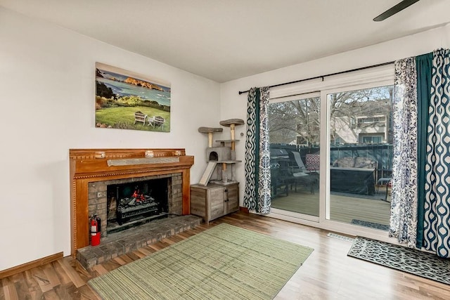 interior space featuring a brick fireplace, baseboards, and wood finished floors