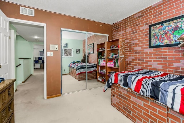 bedroom featuring visible vents, brick wall, a textured ceiling, concrete floors, and a closet