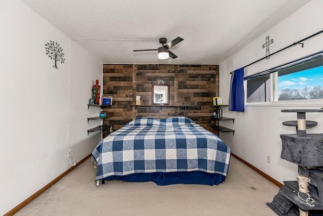 carpeted bedroom with a textured ceiling, an accent wall, baseboards, and wooden walls