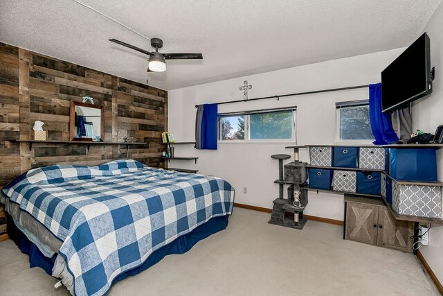 carpeted bedroom with wood walls, a ceiling fan, baseboards, and a textured ceiling