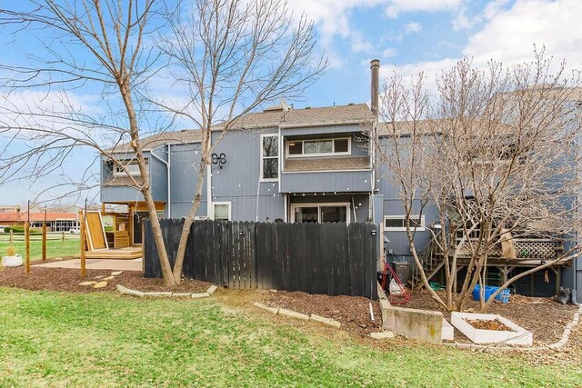 rear view of property featuring a lawn and fence