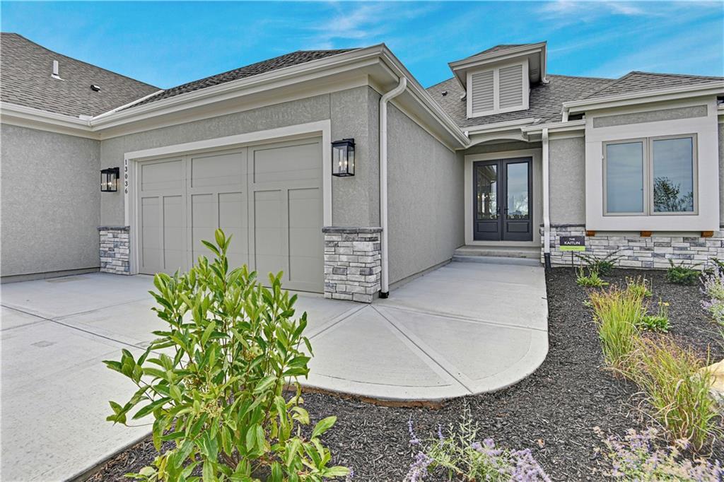 property entrance with concrete driveway, stone siding, an attached garage, french doors, and stucco siding