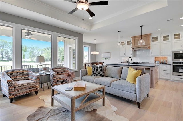 15026 W 129th Ter, Olathe, KS 66062 - living room with a tray ceiling, ceiling fan, light wood finished floors, recessed lighting, and ornamental molding