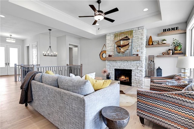 15026 W 129th Ter, Olathe, KS 66062 - living area with a raised ceiling, light wood-style flooring, a ceiling fan, a stone fireplace, and recessed lighting