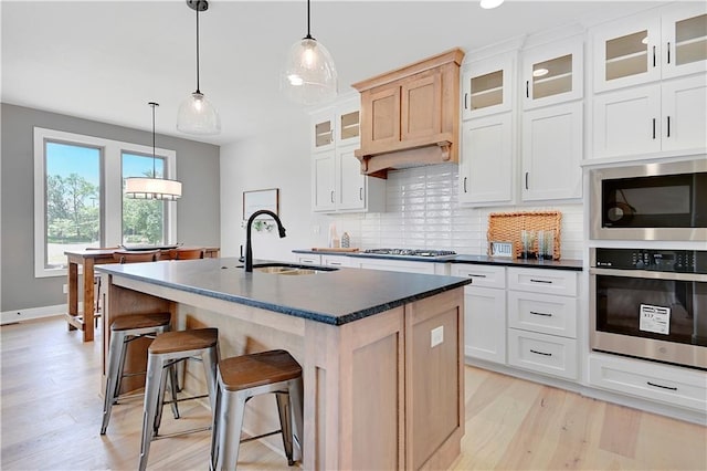 15026 W 129th Ter, Olathe, KS 66062 - kitchen with stainless steel appliances, decorative backsplash, light wood-style floors, an island with sink, and a kitchen bar