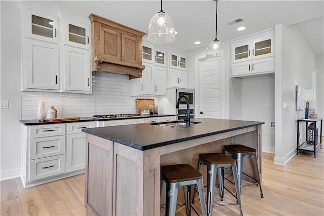 15026 W 129th Ter, Olathe, KS 66062 - kitchen with dark countertops, light wood-type flooring, backsplash, an island with sink, and recessed lighting