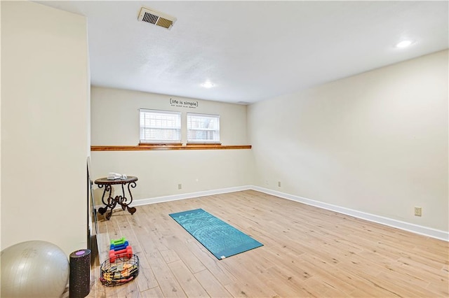 exercise room featuring visible vents, baseboards, and wood finished floors