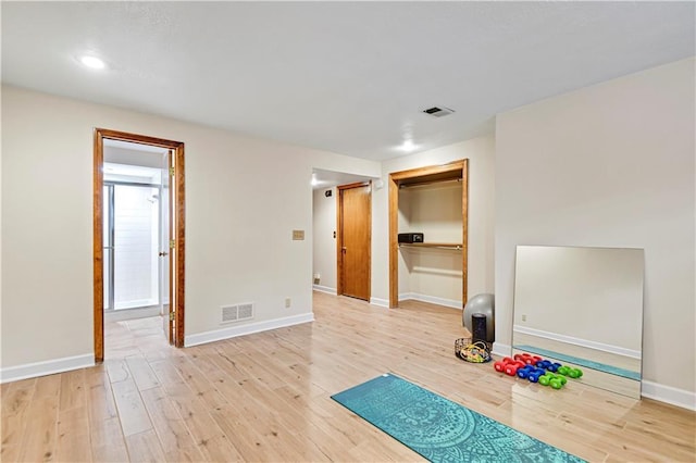 workout area featuring visible vents, baseboards, and light wood finished floors