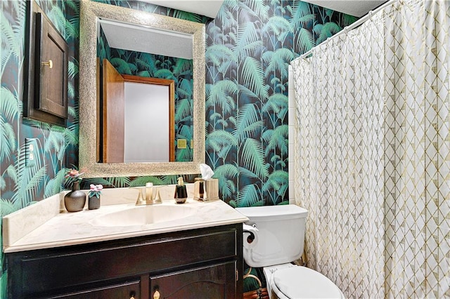 full bathroom with wallpapered walls, toilet, and vanity