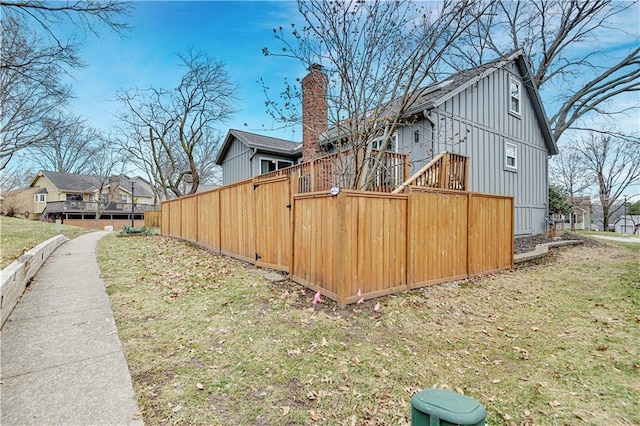 view of side of home with board and batten siding, a chimney, and fence