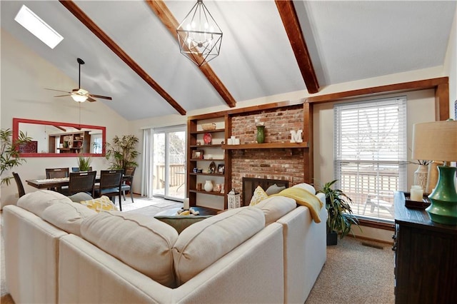 living area with visible vents, ceiling fan with notable chandelier, light colored carpet, a brick fireplace, and vaulted ceiling with beams