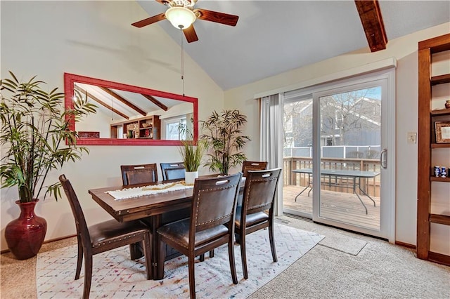 dining room featuring lofted ceiling with beams, baseboards, a wealth of natural light, and light carpet