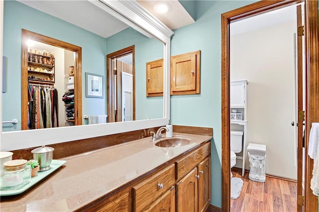 bathroom with toilet, wood finished floors, and vanity