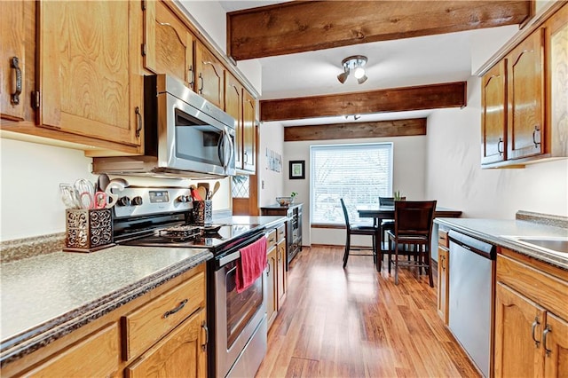 kitchen featuring beam ceiling, brown cabinets, light wood finished floors, and stainless steel appliances